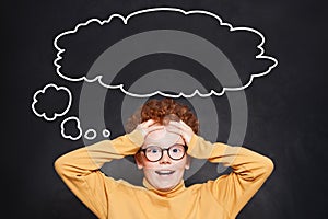 Surprised child with big empty speech cloud bubble on chalkboard background