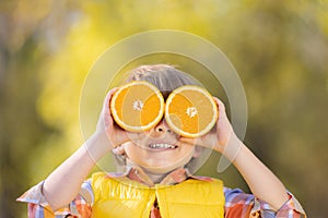 Surprised child holding slices of orange in autumn park