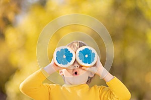 Surprised child holding slices of orange fruit like sunglasses