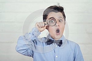 Surprised child looking through magnifying glass