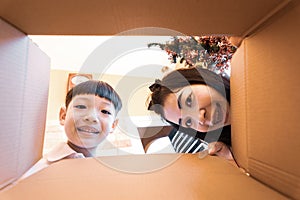 The surprised child and mom unpacking, opening the carton box and looking inside. Unboxing inside view, asian family