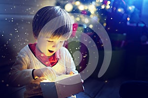 Surprised child opening and looking inside a magic gift