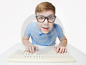 Surprised Child using Computer Keyboard. Teenage Boy Hacker typing on Laptop. Funny Kid In Eye Glasses Study Programming Code