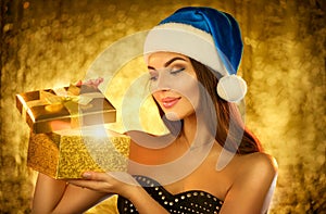 Surprised Christmas Winter Woman opening magic Christmas Gift box and smiling over golden backgroun