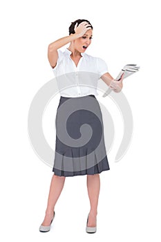 Surprised classy businesswoman holding newspaper