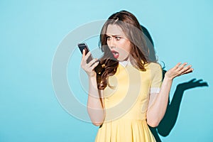 Surprised confused woman in dress looking at mobile phone