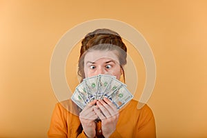 A surprised and crazy girl looks at the money she holds in her hands