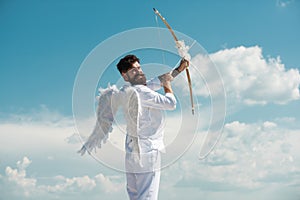 Surprised cupid with wings aiming with bow and arrow on a sky background. Funny valentines day concept. Humor comical
