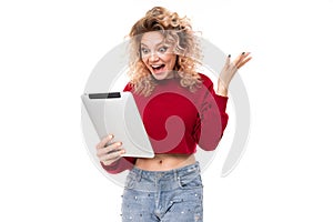 Surprised curly blonde with on a tablet on a white background