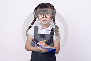 Surprised cute child in eyeglasses writing in notebook using pencil. Five or six years old  school kid,  on white