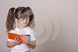Surprised cute child in eyeglasses, writing in notebook using pencil, keeping mouth wide open. Four or five years, isolated