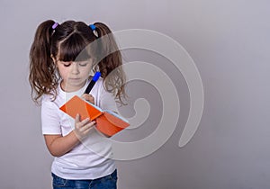 Surprised cute child writing in notebook using pencil, keeping mouth wide open. Four or five years old kid, isolated