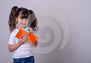 Surprised cute child writing in notebook using pencil, keeping mouth wide open. Four or five years old kid, isolated