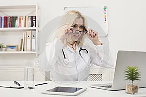 Surprised doctor with glasses sitting at desktop