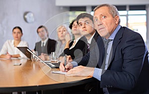 Surprised elderly businessman watching presentation during business meeting