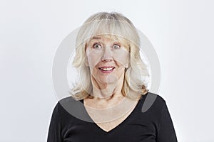 Surprised elderly woman. Beautiful lady in a black sweater smiles. Positivity and joy of life. Close-up. White background