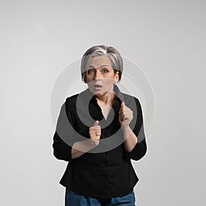 Surprised elderly woman in black looks into camera frightened. Emotions concept