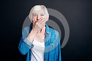Surprised elderly woman standing on black background