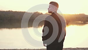 Surprised emotional man looking into the camera. Portrait of a handsome young guy on the beach during sunset. slow