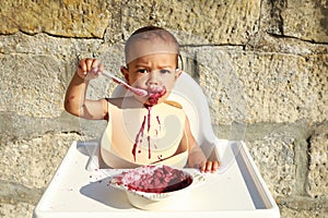 Surprised essy baby boy eating blueberry cake