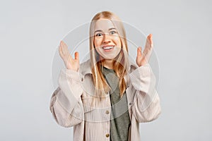 Surprised and excited girl smiling from happy news, raising hands up, staring at camera pleasantly astounded, wears casual clothes