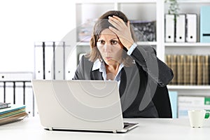 Surprised executive lady making mistake on laptop at office