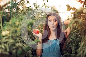 Surprised Farm Girl Holding a Tomato inside a Greenhouse