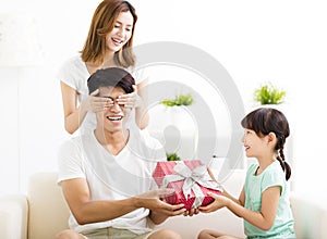 Surprised Father receiving gift box from wife and daughter