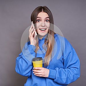 A surprised female in a blue hoodie is talking on the phone