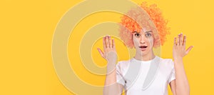 surprised freaky woman in curly clown wig with raised hands, surprise. Woman isolated face portrait, banner with copy