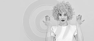 surprised freaky woman in curly clown wig with raised hands, surprise. Woman isolated face portrait, banner with copy