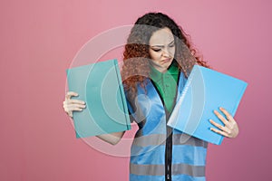 Surprised, frown woman standing, looking down, holding folders by hands, showing.