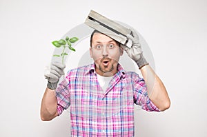 Surprised funny male gardener with plant, isolated on white background. Amazed male farmer