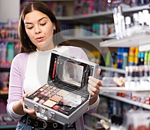 Surprised girl choosing travel cosmetics set at cosmetics department