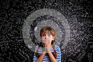 Surprised girl, hands on mouth, blackboard with mathematical symbols