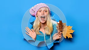 Surprised girl in hat with maple leaves looking through paper hole. Autumn sale. Discount. Season sales.