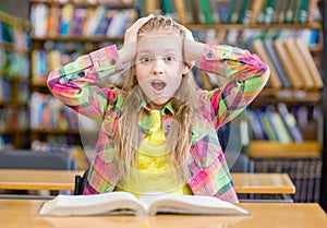 Surprised girl reading a book in the library