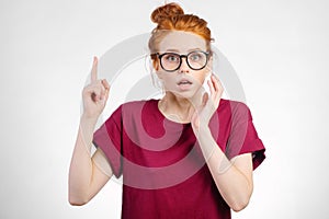 Surprised girl showing copy space with finger white background. girl pointing up