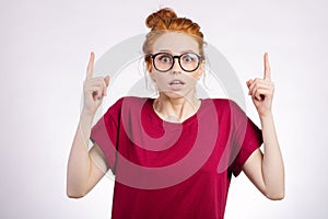 Surprised girl showing copy space with finger white background. girl pointing up