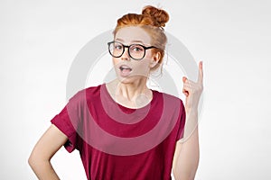 Surprised girl showing copy space with finger white background. girl pointing up