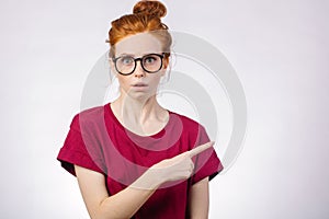 Surprised girl showing empty copy space with her finger white background