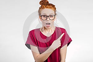 Surprised girl showing empty copy space with her finger white background