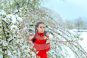 Surprised Girl By Snow Covering Spring Flowers in Blossoming Tree
