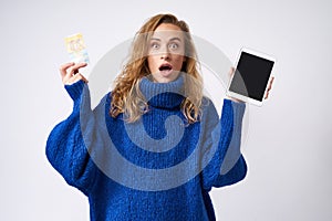 Surprised girl with tablet and money in hand