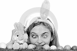 Surprised girl wear bunny ears on Easter day. Young woman with painted eggs on green grass, spring. Happy Easter concept