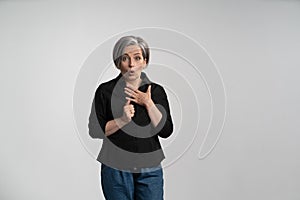 Surprised graying woman in a black shirt on a white background. Sale discount concept. Advertisement blank with copy