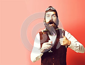 Surprised handsome bearded pilot on red studio background