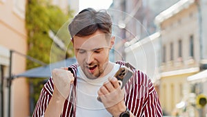 Surprised handsome man use smartphone loses, bad news, fortune loss fail outdoors in city street