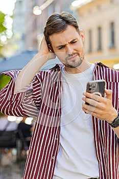 Surprised handsome man use smartphone loses, bad news, fortune loss fail outdoors in city street