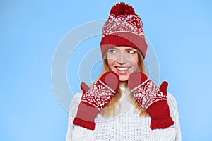 Surprised happy beautiful woman looking sideways in excitement. Christmas girl wearing knitted warm hat and mittens, on b